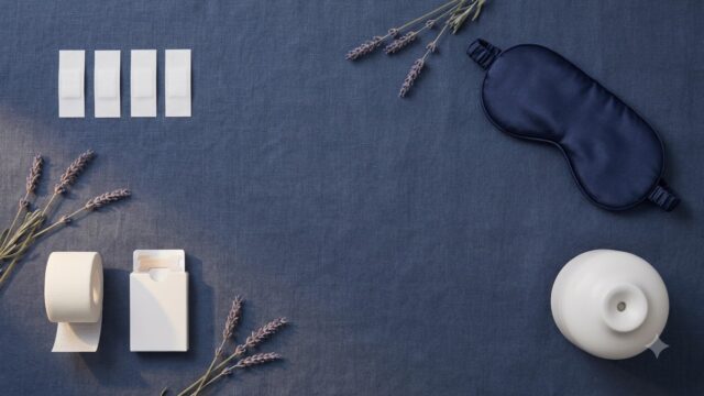 White adhesive strips and medical tape next to nasal strips, a humidifier and a sleep mask on a navy surface